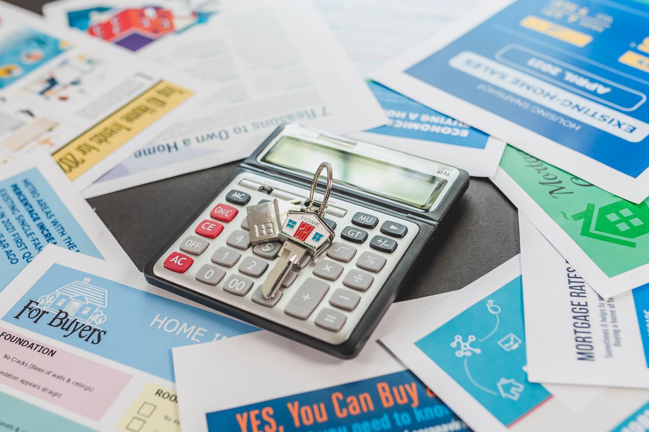 why-choose-us A calculator and real estate flyers depicting financial planning for home buyers.